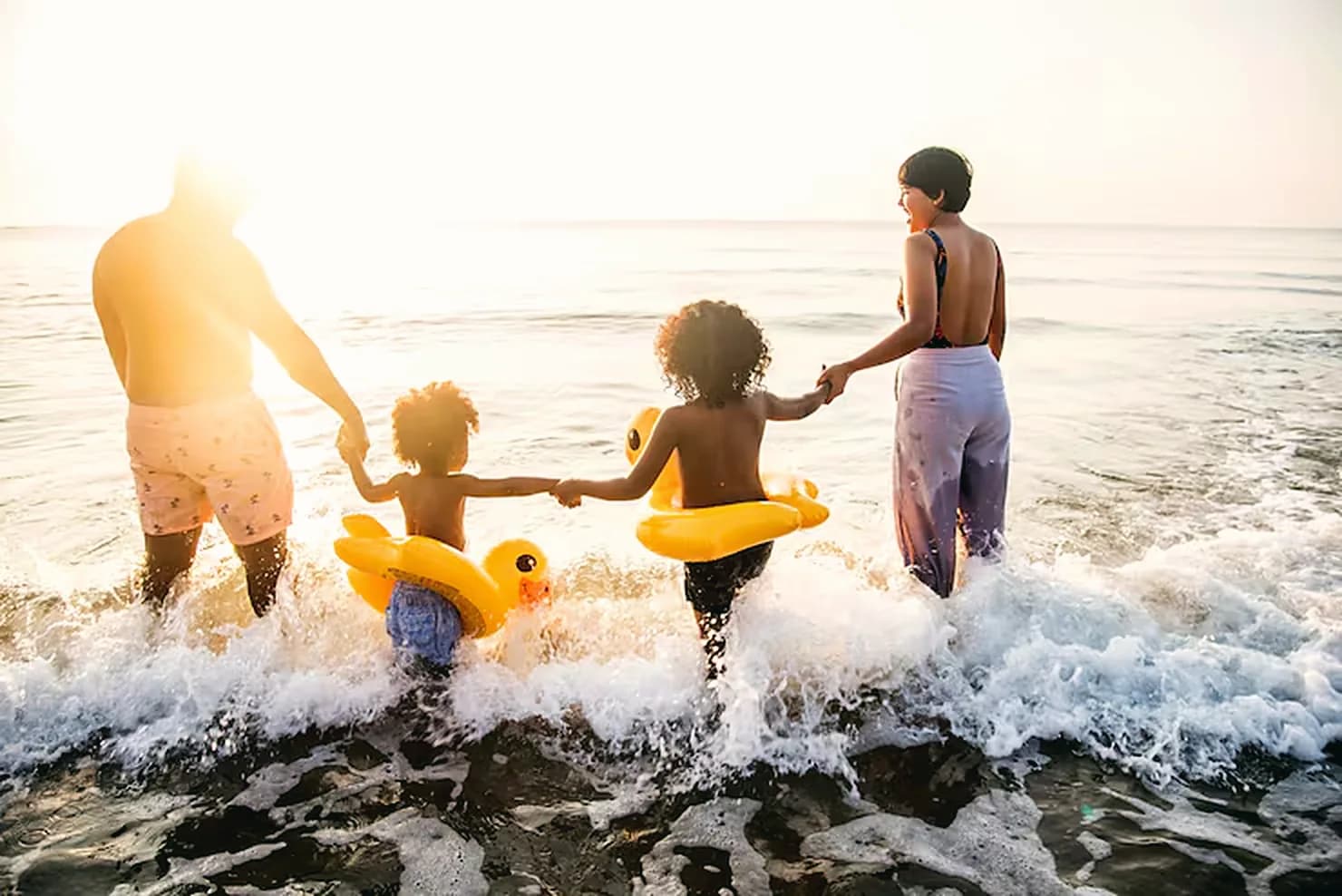 A family walking into the surf together at sunrise