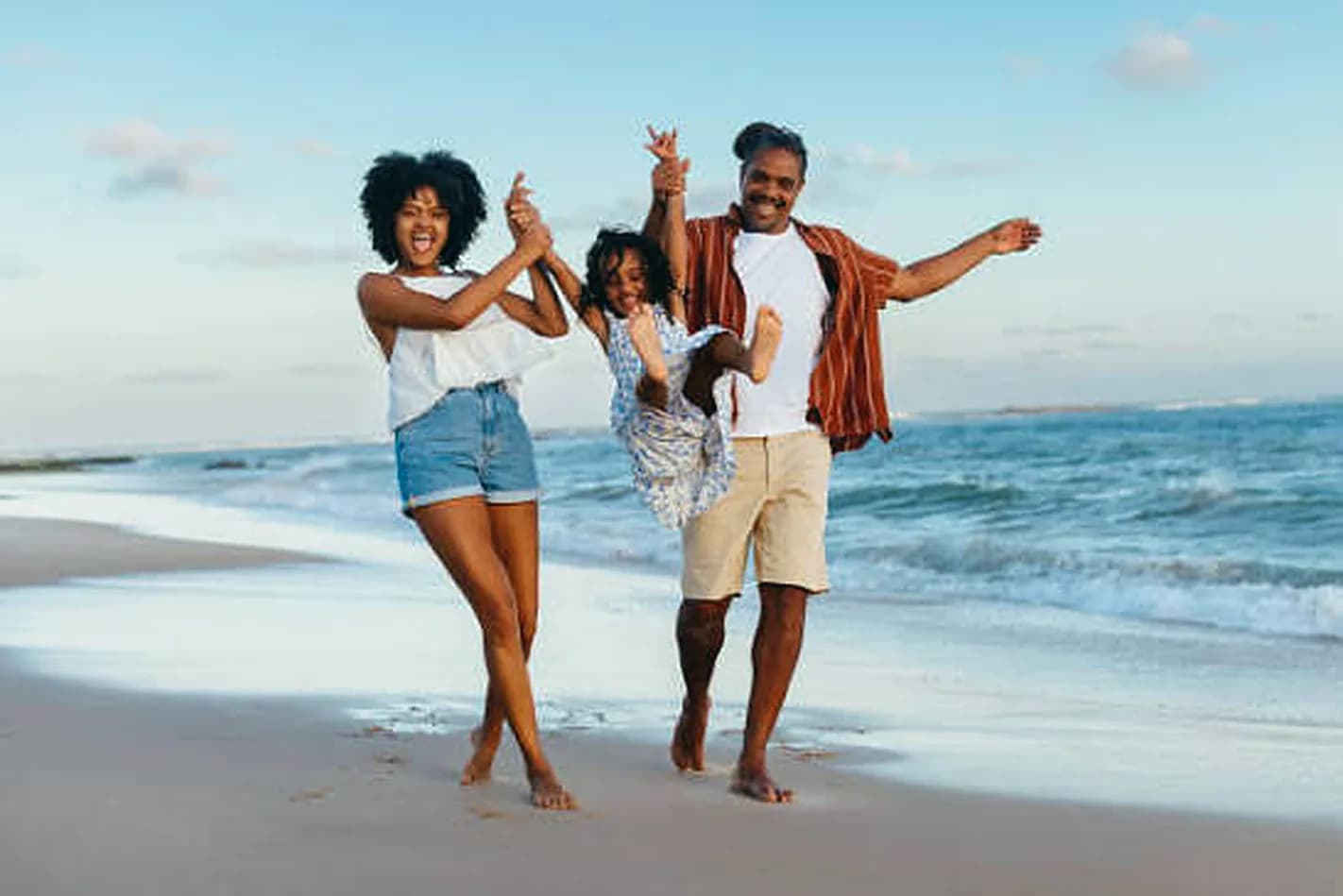 Parents swinging their daughter between them on the beach