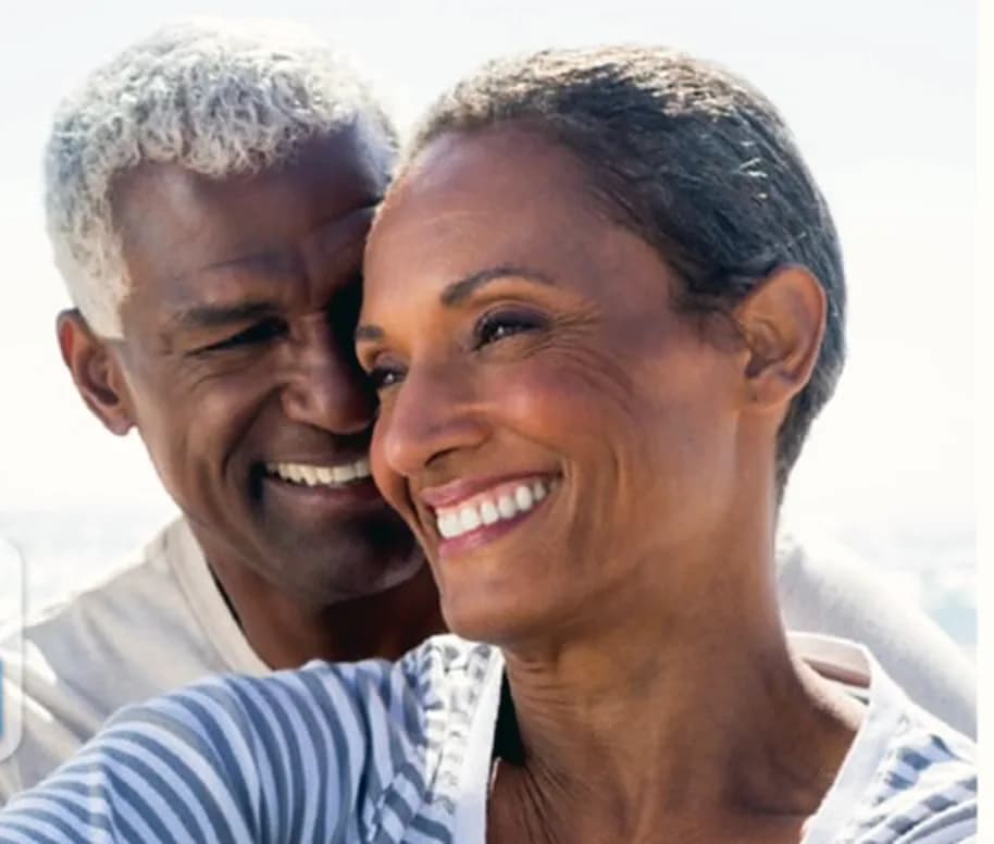 An older couple smiling together by the sea